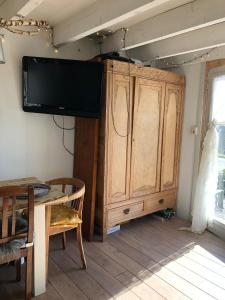 a tv hanging on a wall next to a wooden cabinet at De Knol in Hoek