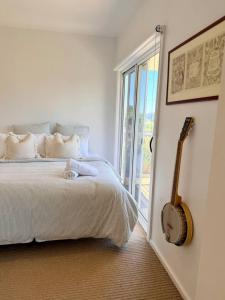 a bedroom with a bed and a guitar next to a window at Shorebreak Port Campbell in Port Campbell