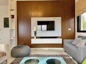 a living room with a couch and a tv on a wall at Les Palmiers Kfar Aabida in Fad‘ūs