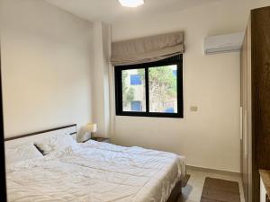 a bedroom with a white bed and a window at Les Palmiers Kfar Aabida in Fad‘ūs