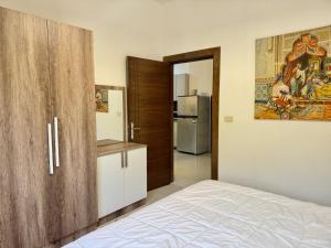 a bedroom with a bed and a kitchen with a refrigerator at Les Palmiers Kfar Aabida in Fad‘ūs