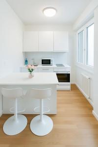 a white kitchen with a white counter and stools at Chailly The Minimalist Lausanne in Lausanne