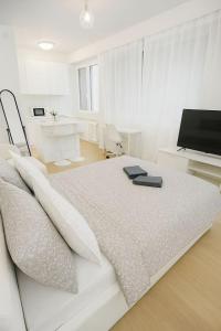 a white bedroom with a bed and a television at Chailly The Minimalist Lausanne in Lausanne