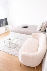 a white bedroom with a chair and a bed at Chailly The Minimalist Lausanne in Lausanne