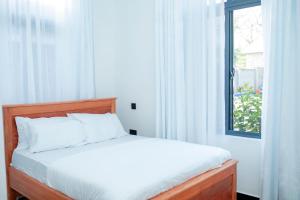 a bed in a bedroom with a window with white curtains at Kilistone Apartments in Uru +36 photos