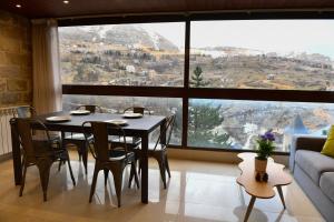 a dining room with a table and chairs and a large window at Aspen - Duplex 1-BR in Faraya in Fārayyā