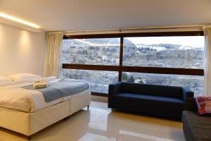 a bedroom with a bed and a couch and a large window at Aspen - Duplex 1-BR in Faraya in Fārayyā