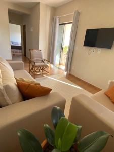 a living room with a couch and a tv at Casa Portal Carrancas in Carrancas