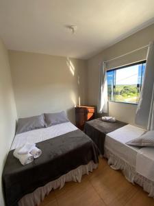 a bedroom with two beds and a window at Casa Portal Carrancas in Carrancas
