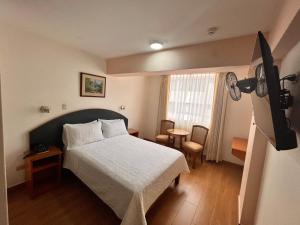 a bedroom with a white bed and a window at Hotel Anthony's in Lima