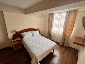 a bedroom with a white bed and a window at Hotel Anthony's in Lima