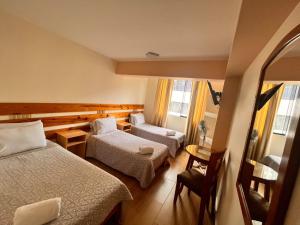 a hotel room with two beds and a chair at Hotel Anthony's in Lima