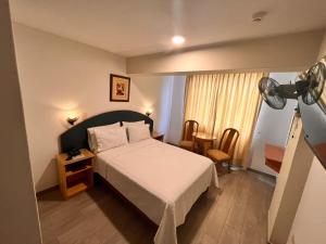 a bedroom with a bed and a lamp and a table at Hotel Anthony's in Lima