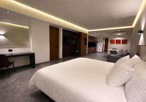 a bedroom with a large white bed and a living room at Hotel Suites Regente Cholula in Cholula