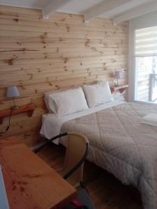 a bedroom with a bed and a wooden wall at Alojamiento junto al mar in Chaitén
