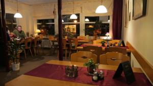 a restaurant with tables and chairs and a man in the background at Hotel zur Post in Wieda