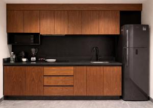 a kitchen with wooden cabinets and a refrigerator at Hotel Suites Regente Cholula in Cholula