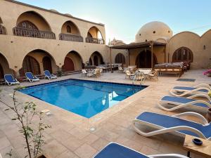 a pool in a courtyard with chairs and tables at Sultana Palace in ‘Ezbet Abu Ḥabashi