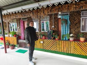a man standing in front of a house with plants at Bamboo Queen Homestay Rongo in Kumai