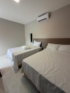 a bedroom with two beds and a air conditioner on the wall at Loft Brisas do Caeté in Bragança +16 photos