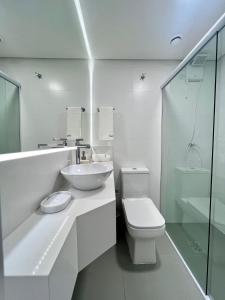 a white bathroom with a sink and a toilet at Casa Veleiro in Florianópolis