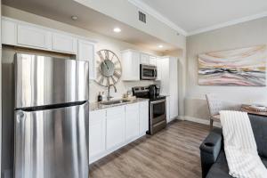 a kitchen with a stainless steel refrigerator and white cabinets at Stunning Apartment w Panoramic Downtown Views! in McKinney