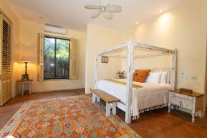 a bedroom with a white canopy bed and a bench at Casa Tara Villa Oceanfront Oasis Private Beach in Cruz de Huanacaxtle