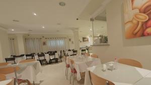 a dining room with white tables and chairs at Hotel Montana Serra Negra in Serra Negra