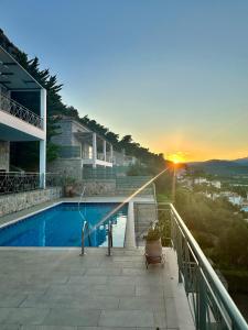 a house with a swimming pool on a balcony with the sunset at Villa Korina in Nea Epidavros