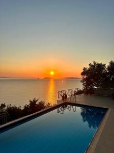 a swimming pool with a sunset in the background at Villa Korina in Nea Epidavros