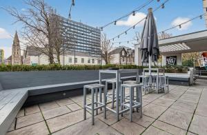 a patio with a table and stools and an umbrella at The Parade - Cardiff - 10 Min Walk to City Centre in Cardiff