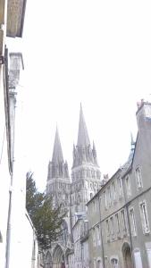 un gran edificio con torres puntiagudas en una calle de la ciudad en Appartement Dumas, en Bayeux