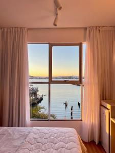 a bedroom with a large window with a view of the water at Casa Veleiro in Florianópolis