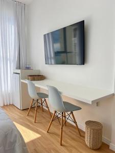 a white desk with two chairs and a tv on a wall at Casa Veleiro in Florianópolis