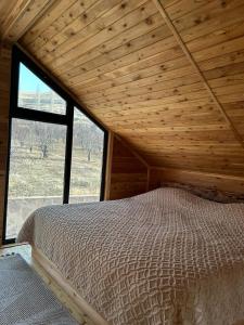 a bed in a wooden room with a large window at Garnu Maran in Garni