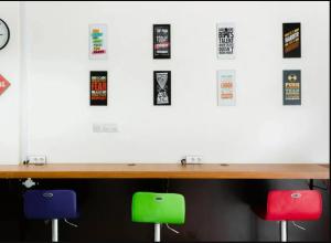 a desk with two stools in front of a wall with stickers at Mutiara Kostel at Batuceper in Poris-lor