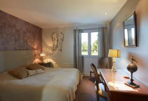 a bedroom with a bed and a desk and a window at The Originals City, Hôtel La Cour Carrée, EU in Eu