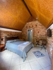a bedroom with a bed and a brick wall at Chalé Ametista in Ouro Preto