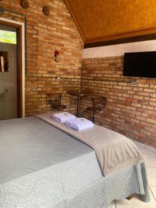 a bedroom with a bed and a brick wall at Chalé Ametista in Ouro Preto