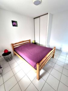 a bedroom with a wooden bed with a purple blanket at Gîte La Vallée RDC Neyrac-les-Bains in Meyras
