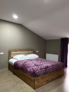 a bedroom with a large bed with a purple comforter at Rachnari Guest House in Gari