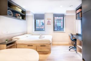 two beds in a room with a desk and two windows at Stylish & Spacious Studio - Prime Briggate Location -Walk Everywhere in Leeds