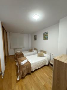 two beds in a room with a white wall at Villa Arán in Negreira