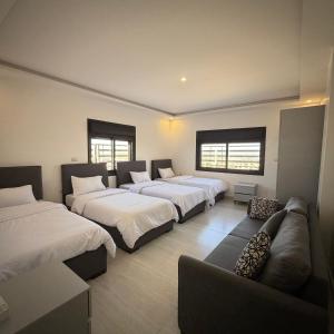 a room with four beds and a couch at ريڨا للأجنحة السكنية Riva suites in Irbid