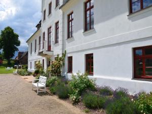 a white building with a bench in front of it at Historic Apartment in Gerdshagen with Garden in Gerdshagen