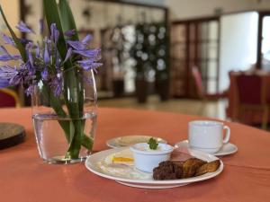 a table with a plate of food and a vase with purple flowers at Hotel Huella Lenca in La Esperanza