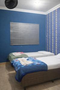 two beds in a room with a blue wall at Jams Hostel - Pousada em Catalão in Catalão