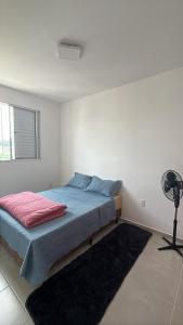 a white bedroom with a bed and a fan at Doce Lar 2 in Pouso Alegre