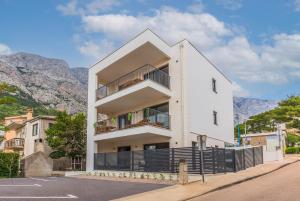 a white building with a balcony and mountains in the background at Luxury Villa MAJA in Baška Voda