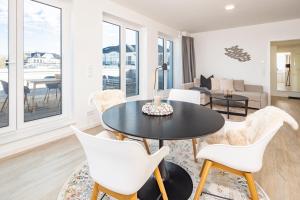 a living room with a black table and white chairs at Ostsee Suite 2 - Penthouse in Niendorf